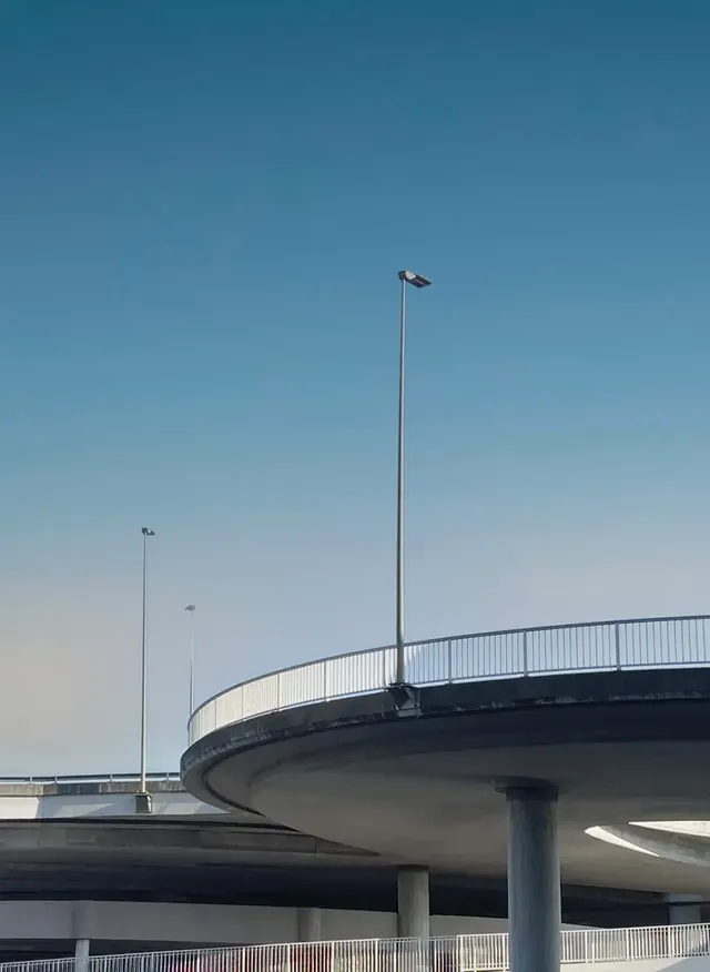 Bretelle d’autoroute en courbe et lampadaires sur ciel bleu.