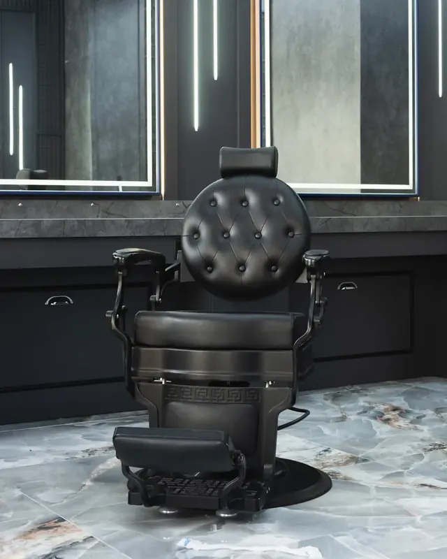 Fauteuil de barbier noir devant un miroir éclairé, sol en marbre.