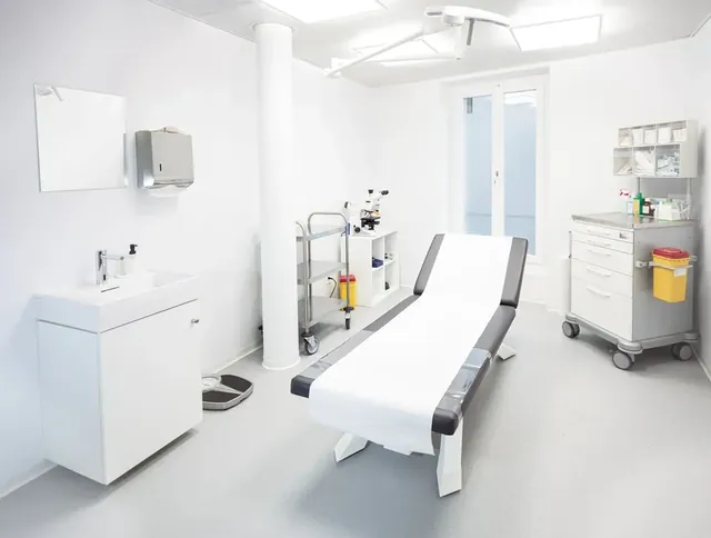Salle de traitement d’un cabinet médical : table d’examen, scialytique et chariot de soins.