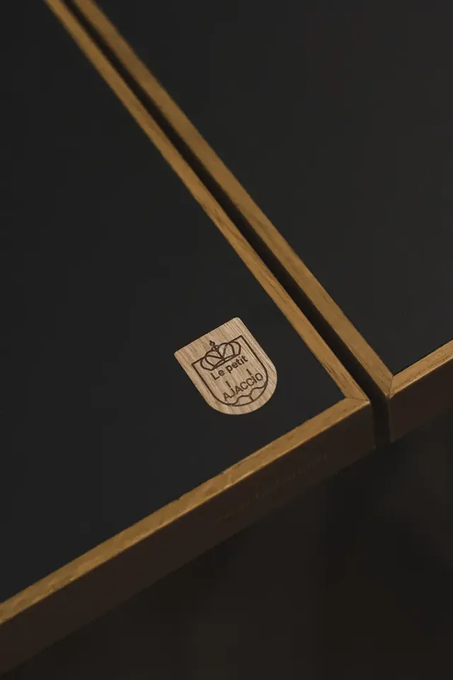 Détail d’un plateau de table noir portant un écusson gravé.