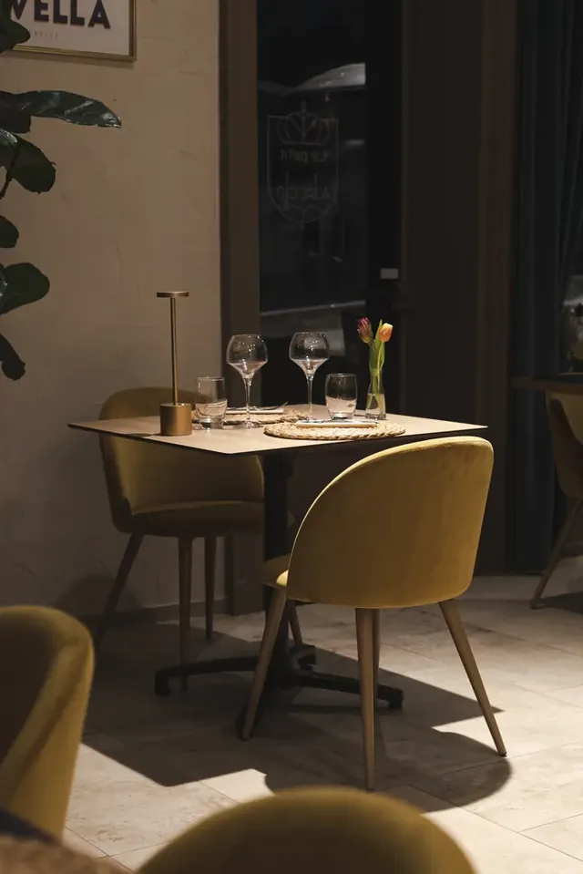 Table dressée pour deux, chaises jaune moutarde, lumière chaude.