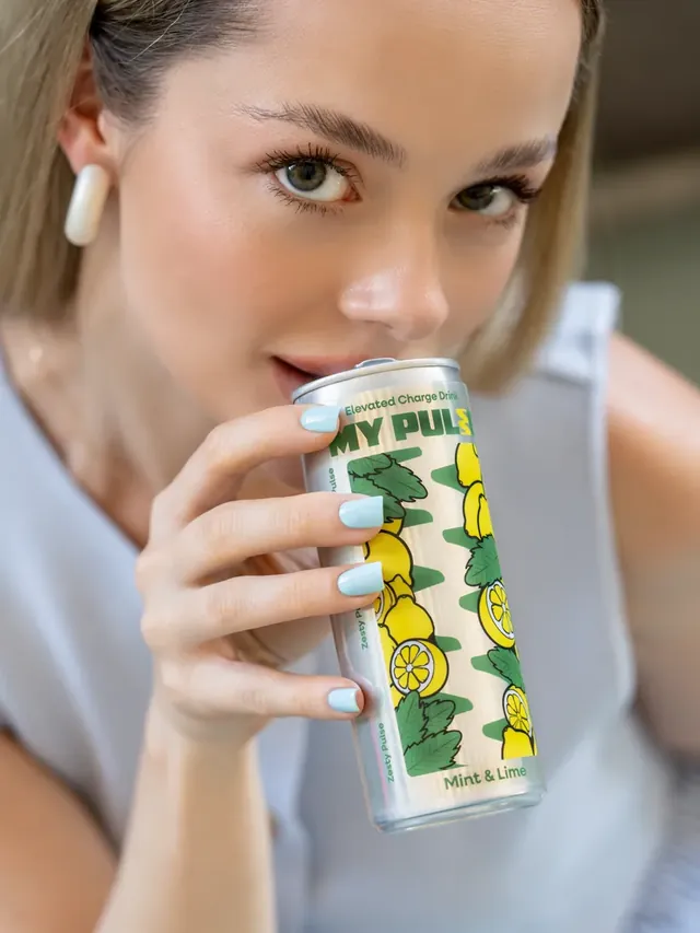 Jeune femme buvant une canette My Pulse menthe et citron vert, en gros plan.