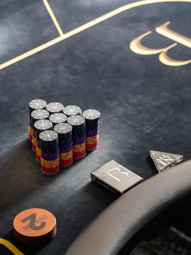 Piles de jetons alignées sur un tapis de jeu sombre.