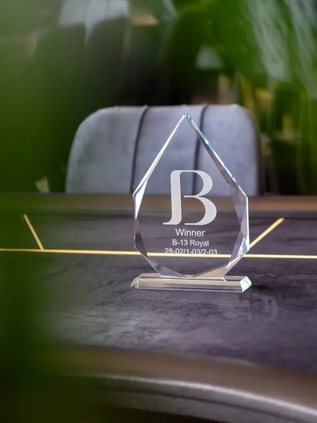 Trophée en verre gravé posé sur une table de jeu.
