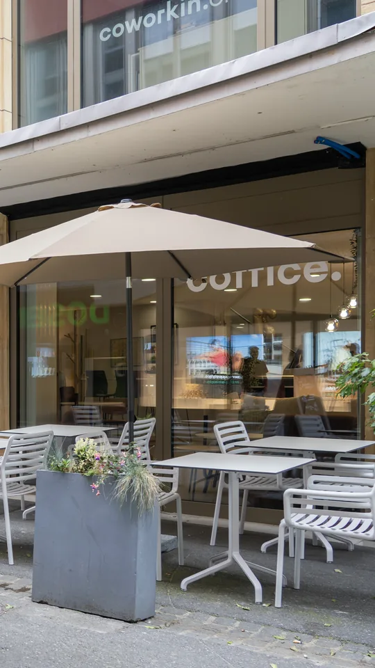 La terrasse du Coffice à Neuchâtel : tables blanches sous un parasol, devant la vitrine au nom du café.